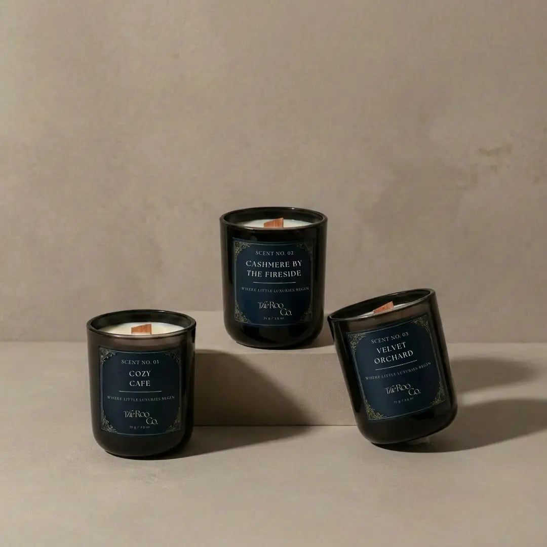 Three luxury mini candles in navy glass with gold detailing displayed in a clean, minimal product composition.