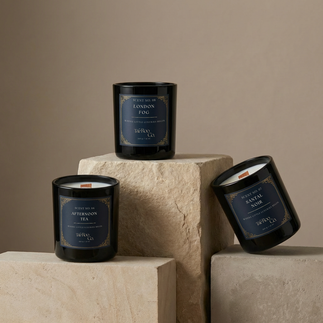 The Roo Co luxury candles including Afternoon Tea, London Fog, and Santal Noir displayed on sculptural cement blocks against a neutral stone backdrop.