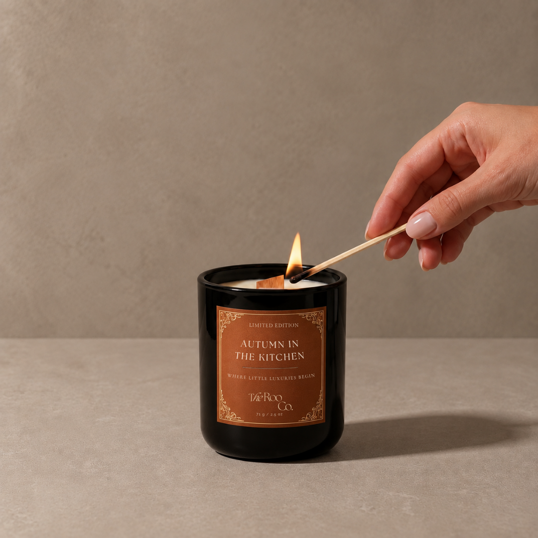Autumn in the Kitchen candle by The Roo Co being lit, featuring creamy coconut-soy wax and a wooden wick.